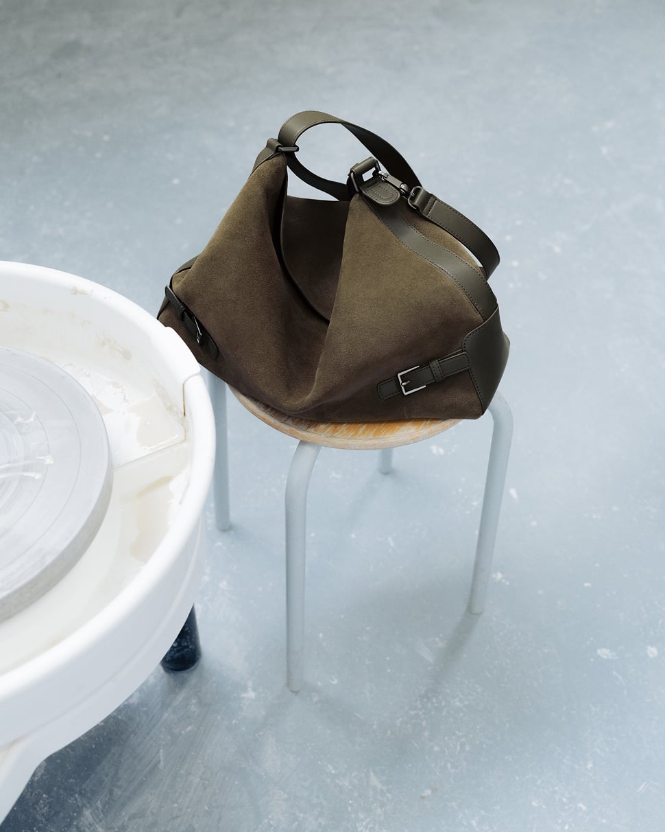A brown PEDRO bag resting on a stool beside a pottery wheel