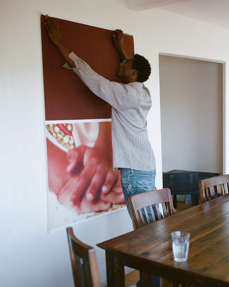 Jabari Wimbley hanging a large textile piece on a wall