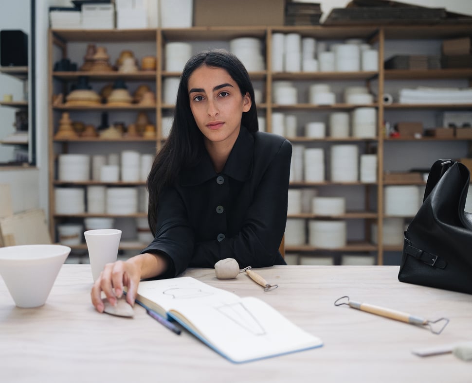 Tahni Bouhadana seated at a worktable in her ceramics studio